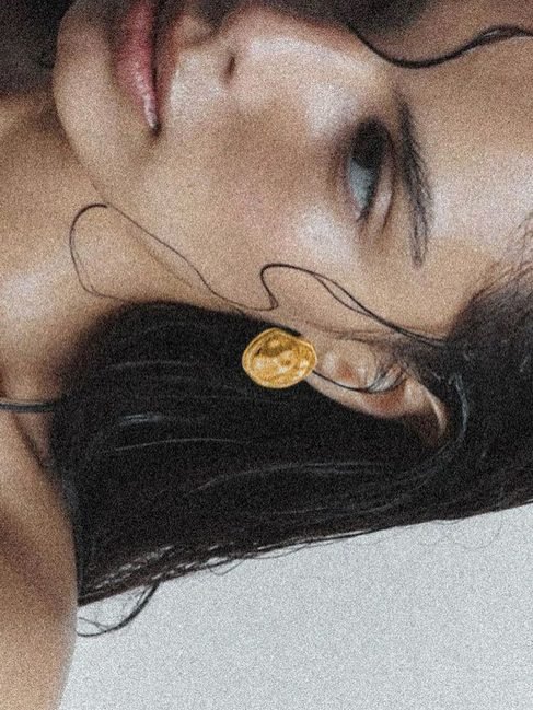 Retrato de una mujer con el pelo mojado y un pendiente dorado